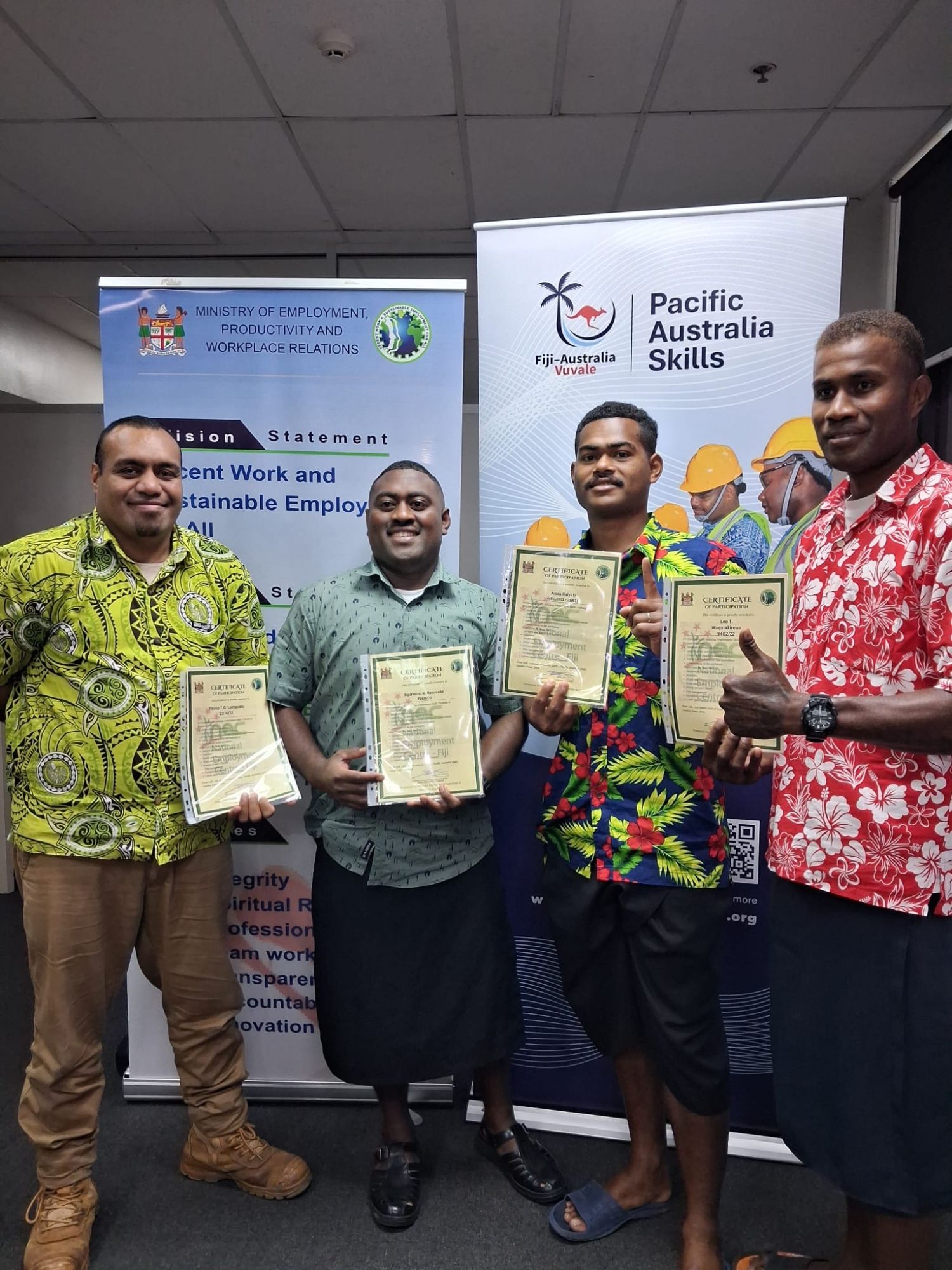 Fiji Ministry of Employment officials and participants holding certificates in front of the Pacific Australia Skills banner