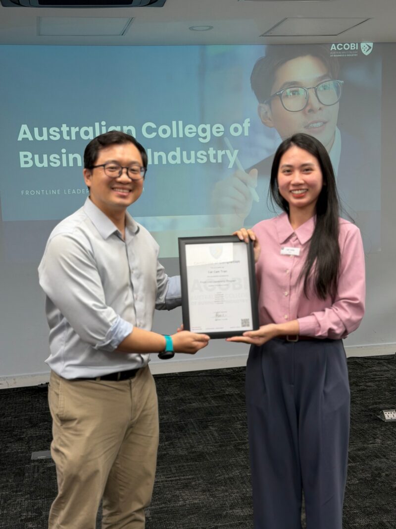 Two participants holding a framed certificate of completion for the Frontline Leadership Program in Vietnam